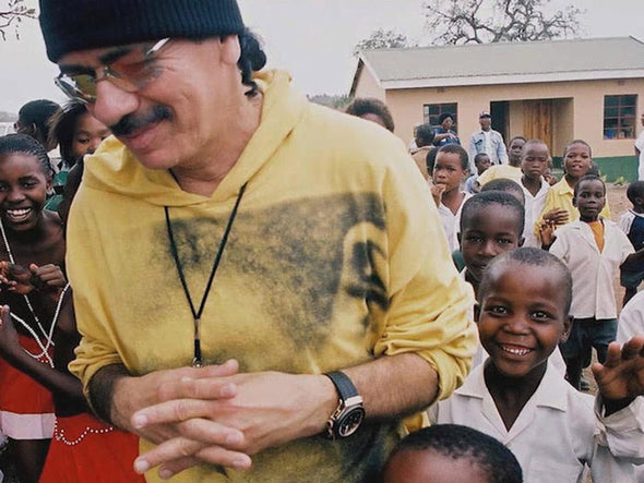 Santana smiling while surrounded by a classroom full of children overseas